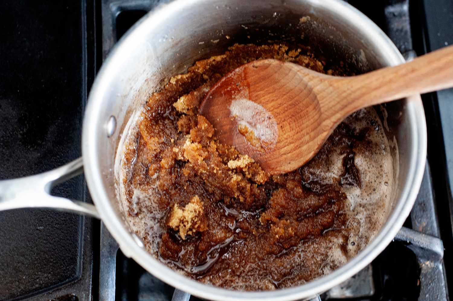 Stirring ingredients to make a butter pecan ice cream recipe in a pot on the stove.