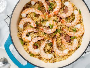 Dirty Rice With Shrimp in a Dutch Oven Surrounded by Glasses of Water and a Plate With Utensils