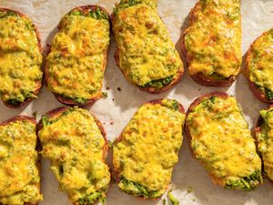 Broccoli and cheddar cheese toasts arranged in rows on a baking sheet