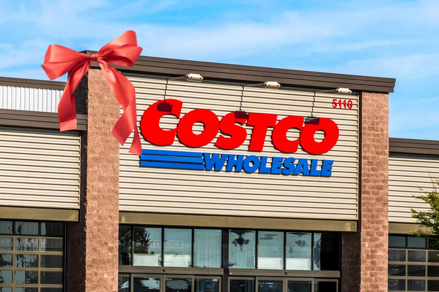 The entrance of a Costco Wholesale store featuring a red bow decoration on the building