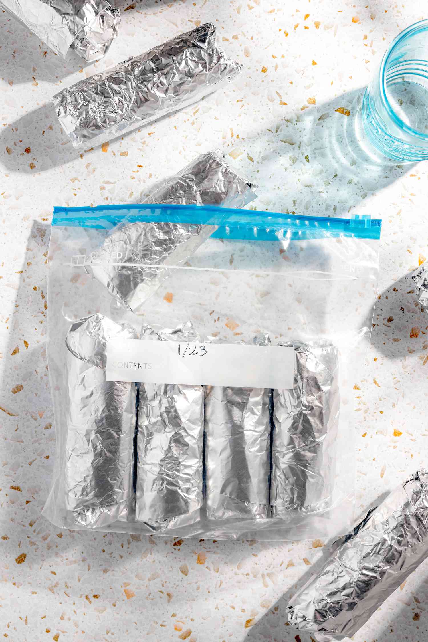 Easy Rice and Beans Freezer Burritos Wrapped in Aluminum Foil (Some on the Counter and Some in a Ziploc Bag)