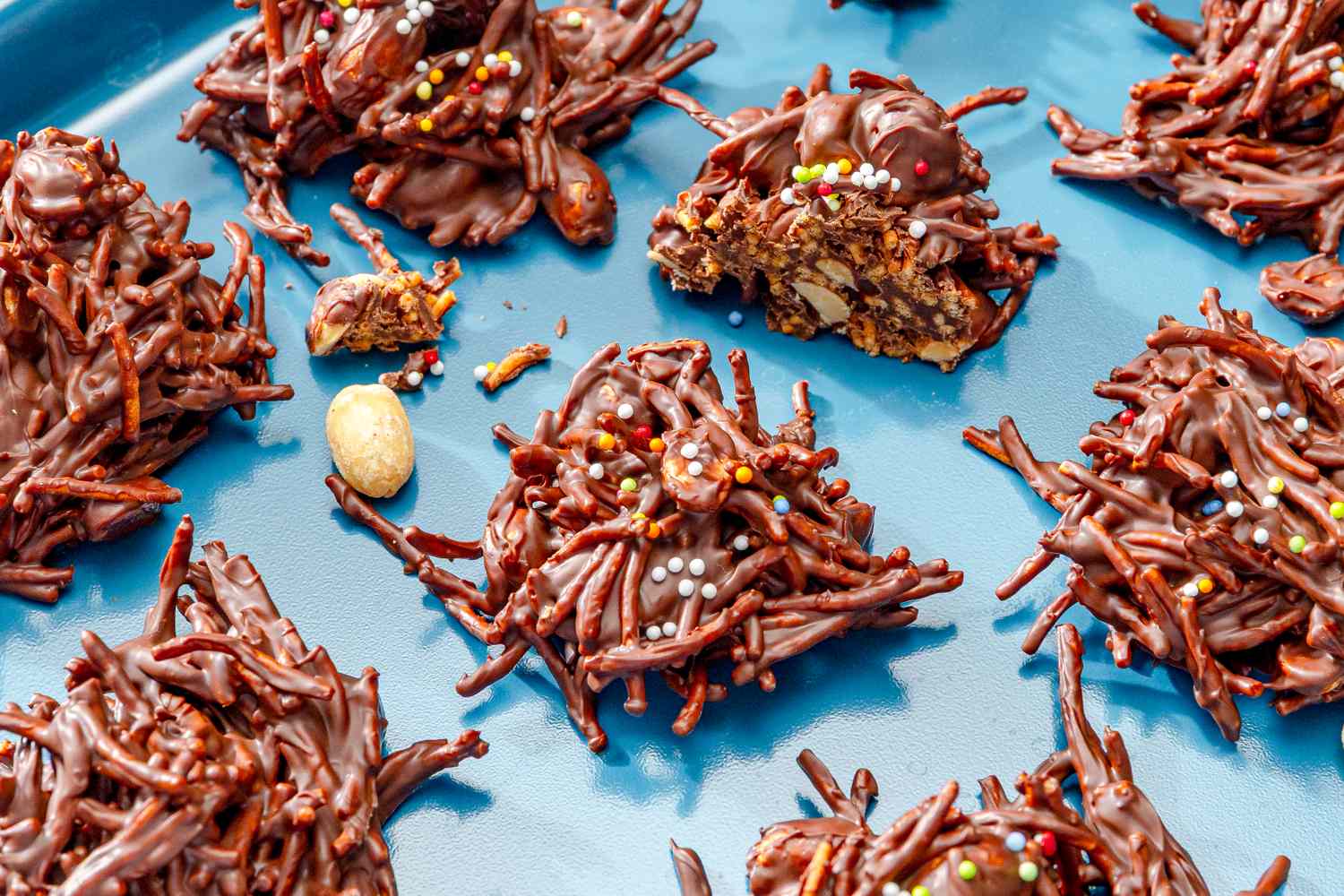 Chocolate chow mein cookies topped with sprinkles assorted on a blue surface