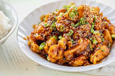 Bowl of Chinese Orange Chicken Next to a Bowl of Rice 