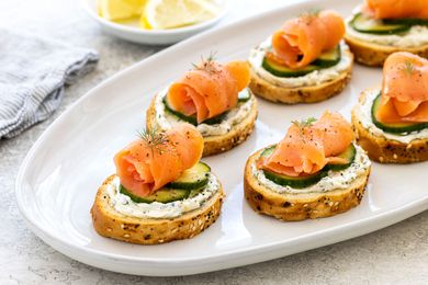 Smoked salmon, cucumber, and cream cheese crostini on a platter.