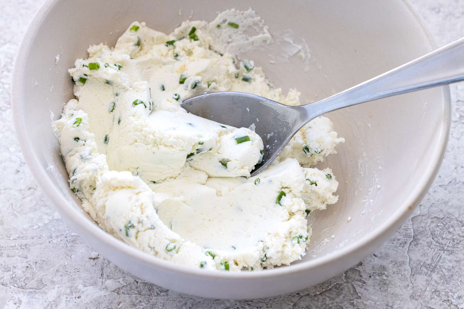 Mixing the cream cheese spread to make goat cheese crostini with mushrooms.