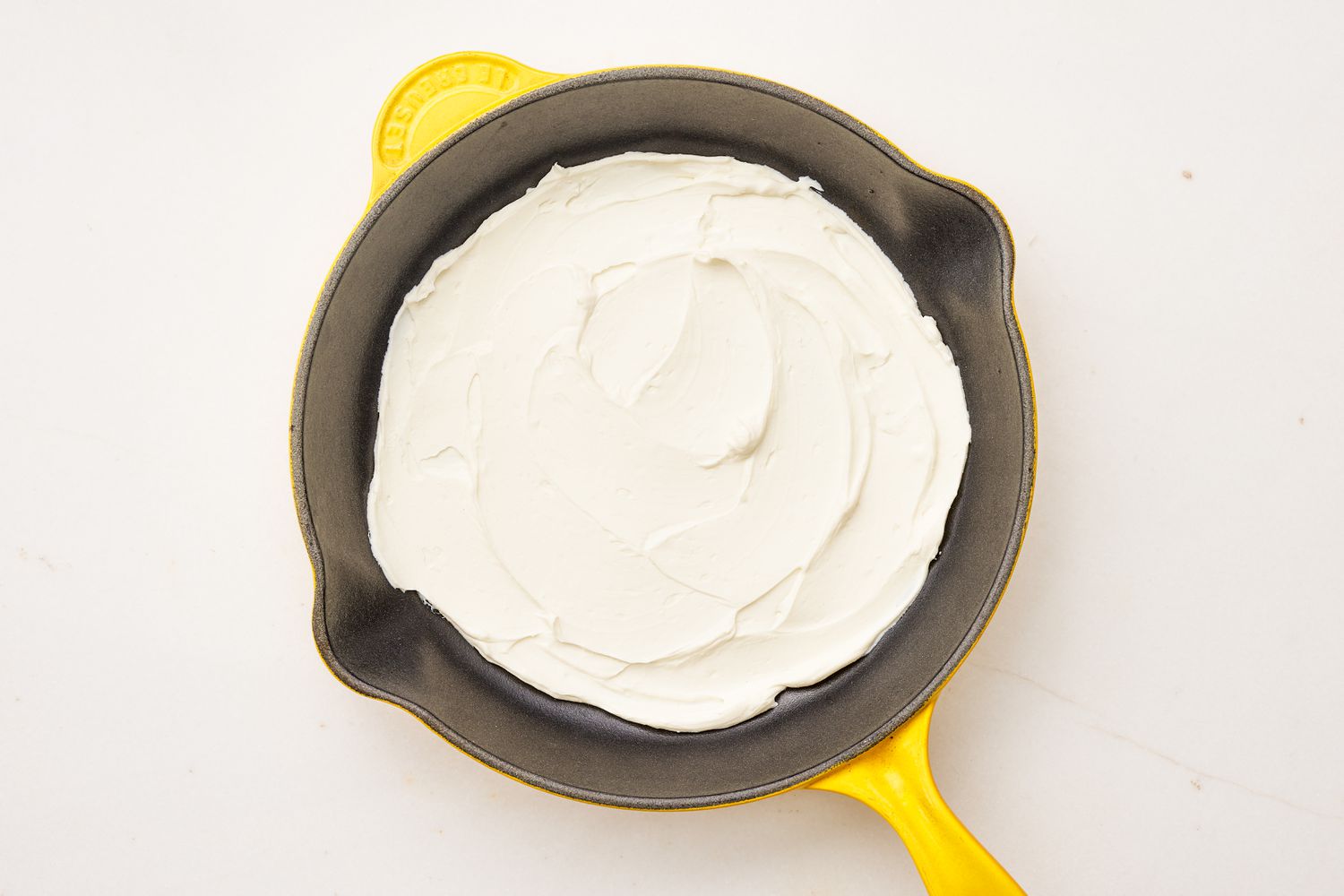 Cream cheese mixture in a cast iron skillet for frito pie dip recipe