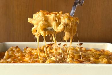 large serving spoon scooping Tini Younger’s Mac and Cheese out of a dish, cheese pull strings hanging