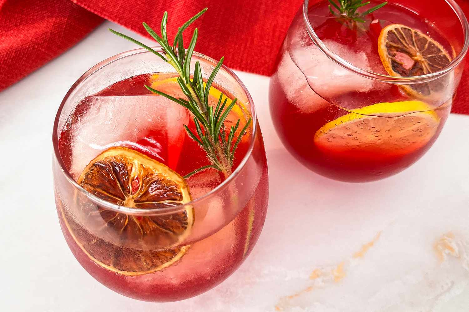 Trader Joe's holiday punch in two glasses garnised with citrus and rosemary