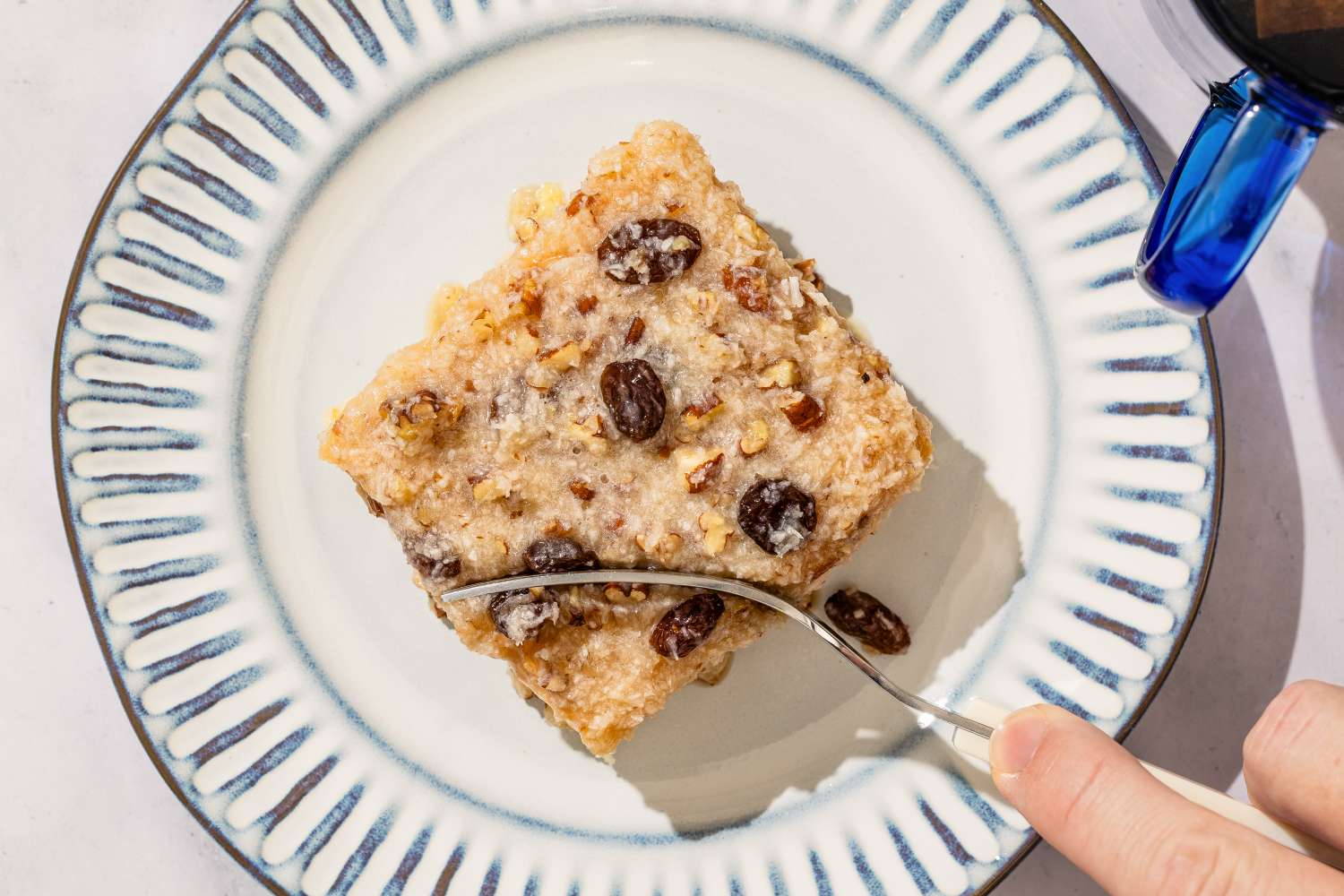 A serving of dessert on a plate with a fork garnished with raisins and nuts