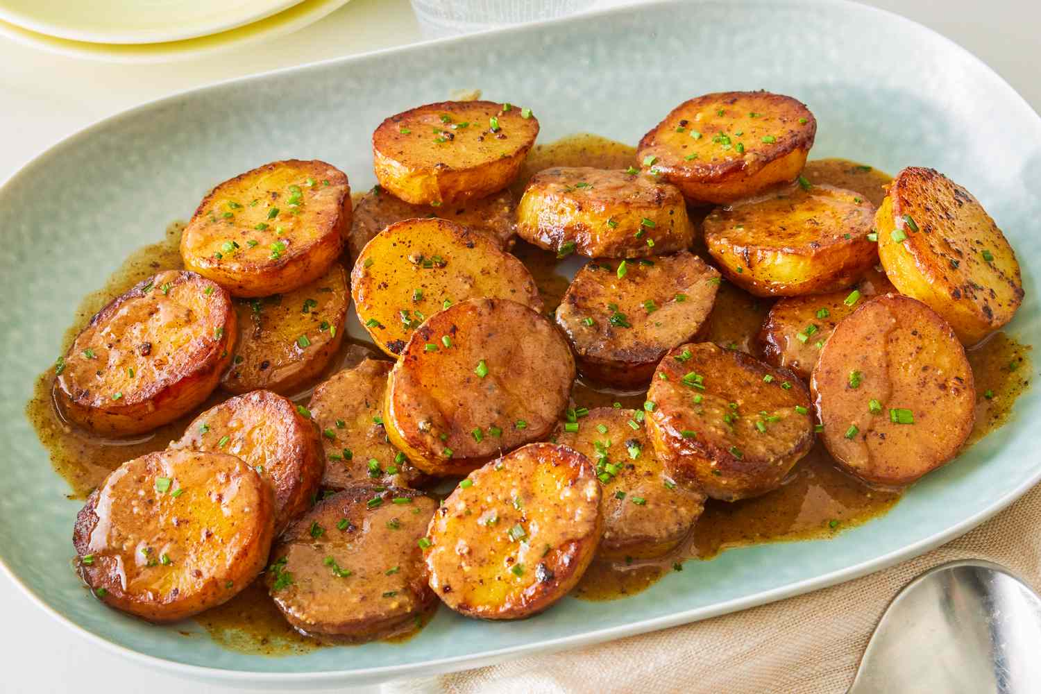 Baked sliced miso melting potatoes in a light blue serving plate, dressed in a miso sauce