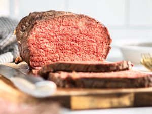 A partially sliced roast beef on a wooden cutting board