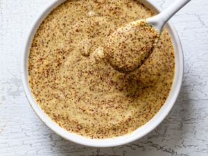 Dijon mustard from scratch in a white bowl with a white spoon.