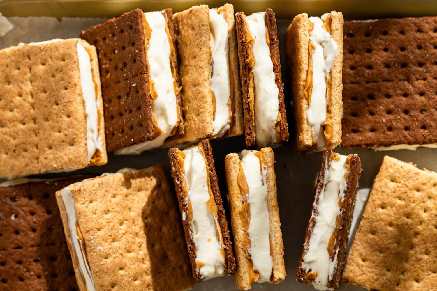 Several frozen graham cracker sandwiches filled with cream and peanut butter arranged on a surface