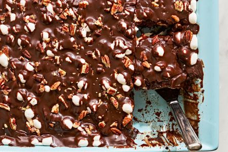 Overhead view of Mississippi Mud Cake in a blue baking dish with a serving utensil and one slice already removed