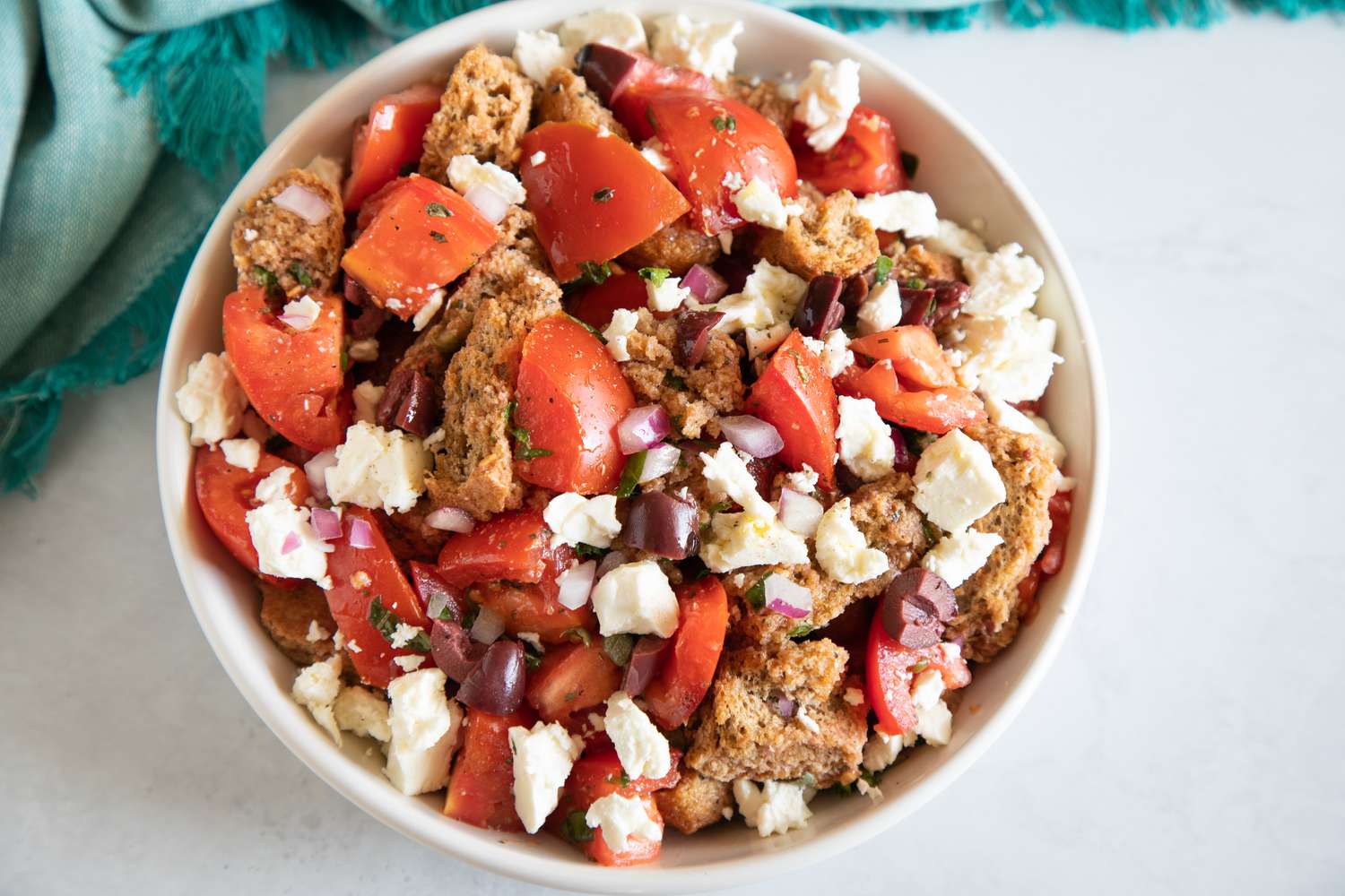 Overhead view of a white bowl filled with Cretan Dakos salad.