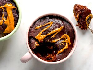 Chocolate peanut butter mug cakes garnished with peanut butter one partially eaten