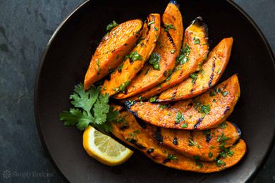 Grilled Sweet Potatoes on a dark plate with cilantro and lime garnish