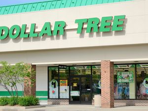The exterior of a Dollar Tree retail store showing the green signage and entrance with promotional displays