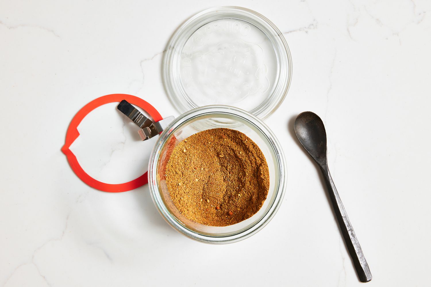 Glass Jar With Homemade Old Bay Seasoning and on the Counter Next to the Jar, a Spoon and the Jar Lid
