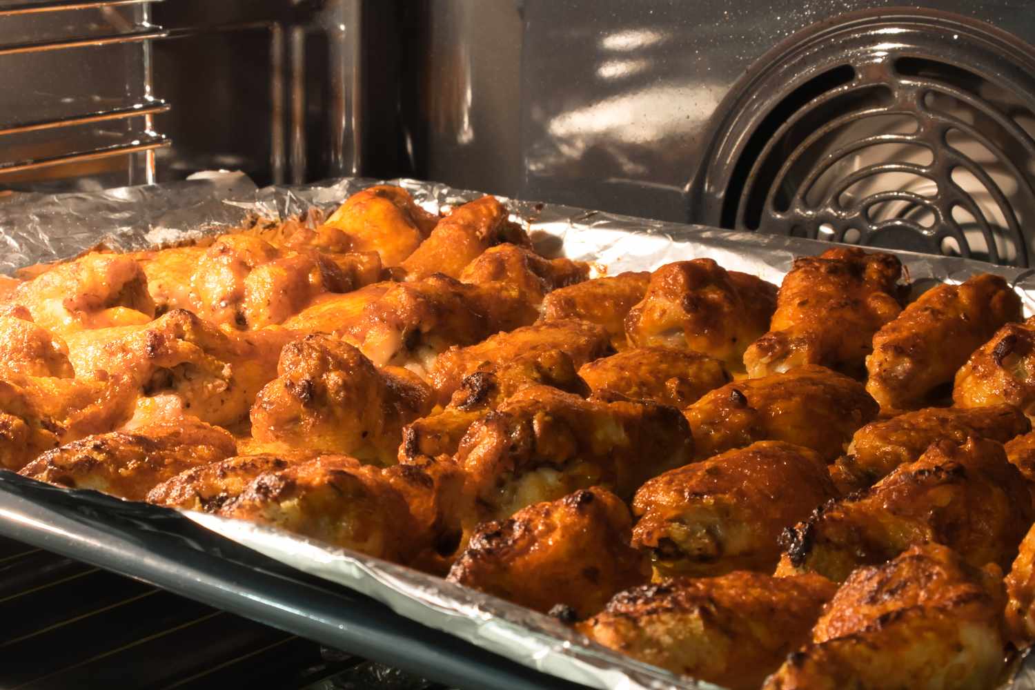 Tray of chicken wings baking in an oven