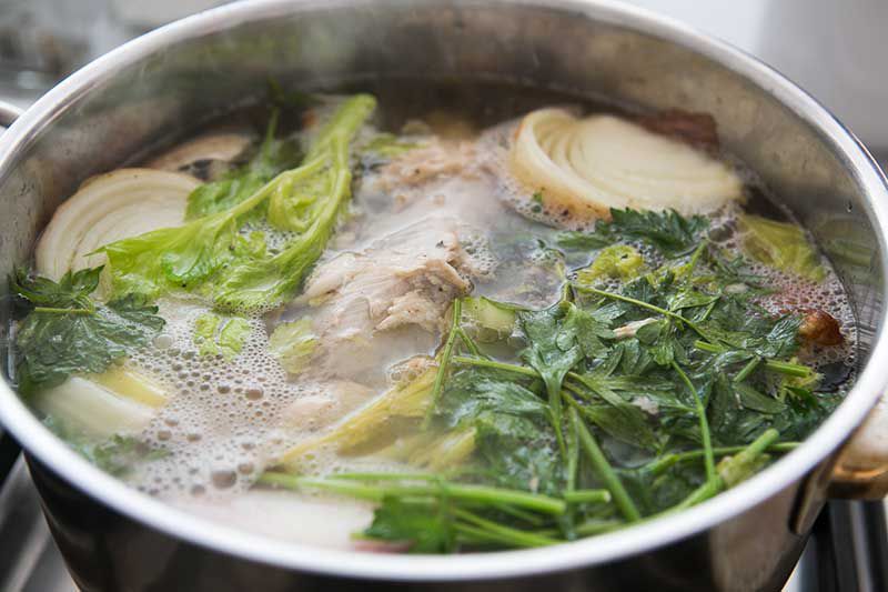 Boiling chicken stock ingredients in a stock pot 