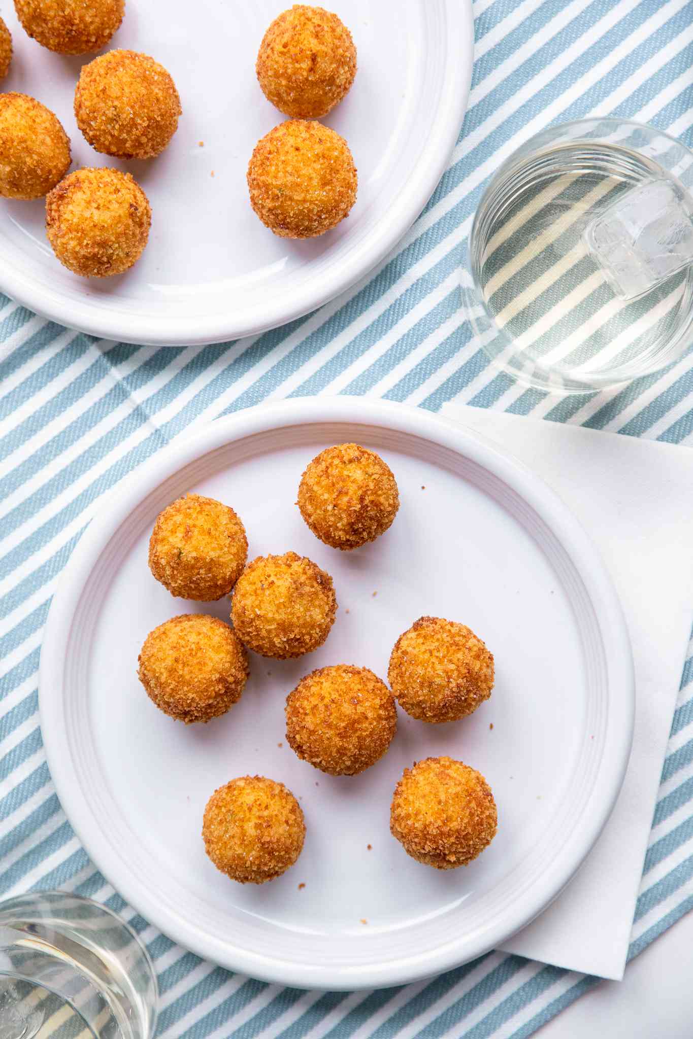 Potato Croquettes on Two Plates at a Table Setting with Glasses of Water