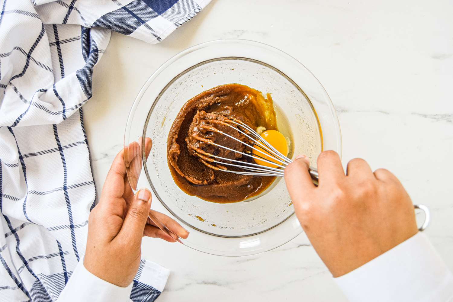 Adding an egg and whisking ingredients in a bowl to make a blondie recipe.