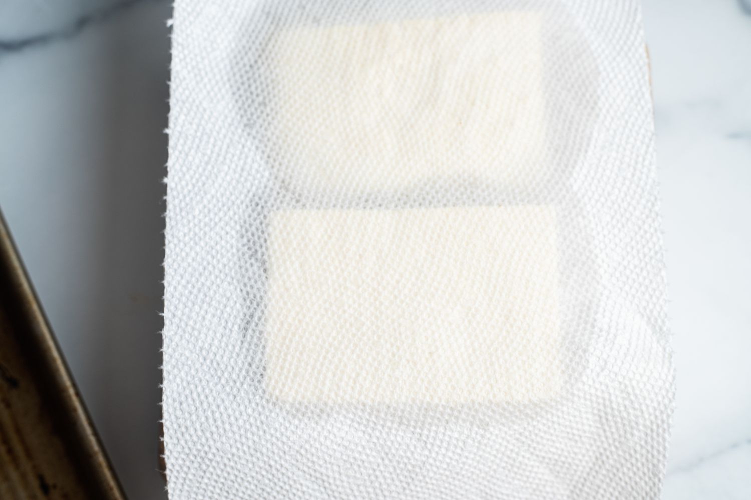 Liquid Removed from Tofu Using a Paper Towel for Sheet Pan Buffalo Tofu Recipe