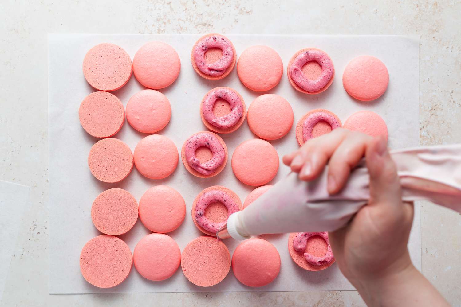 Piping a circle of buttercream on macarons.