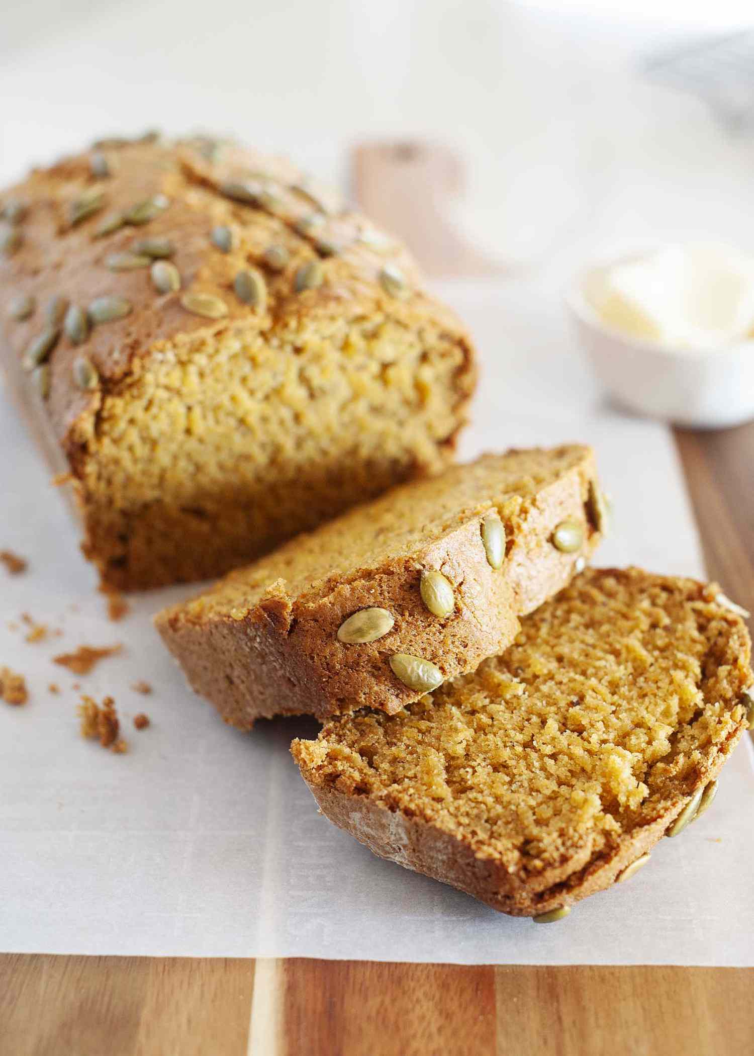 A loaf of the Best Vegan Pumpkin Bread cut into thick slices and set on a cutting board.