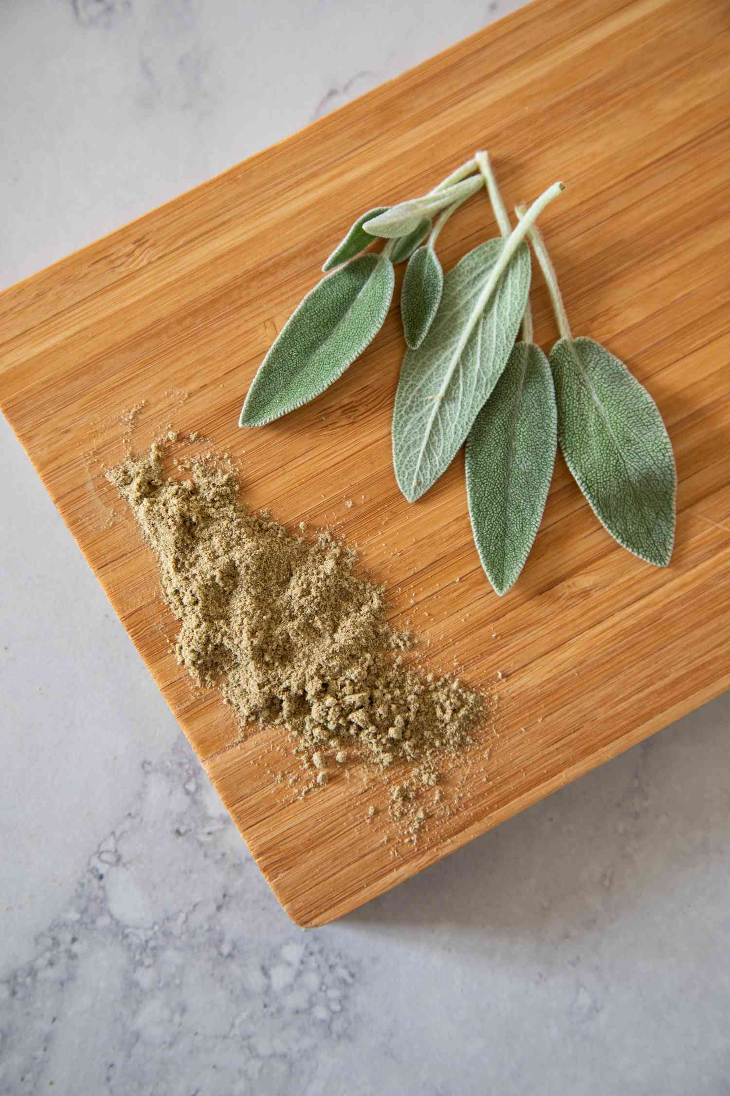 Whole and ground sage on a wood cutting board