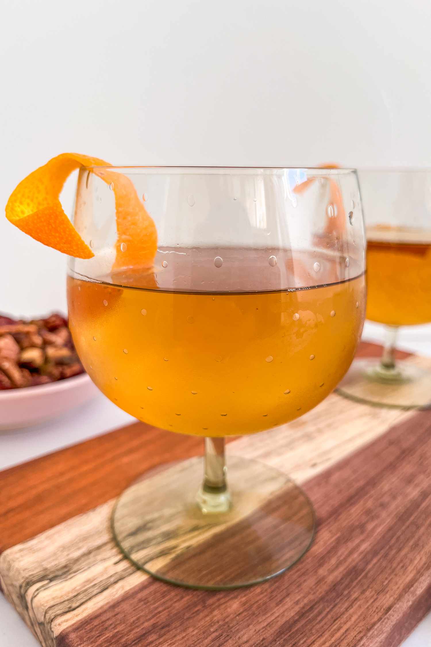 A brownish drink in a stemmed glass with an orange peel garnish