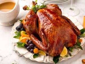 Roasted turkey garnished with fruits and greens served on a decorative platter