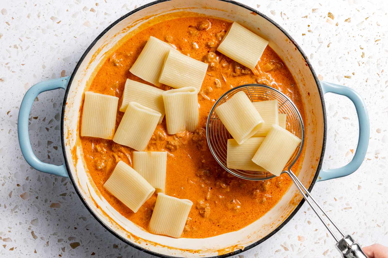Cooked Paccheri Added to Ragu Using a Spider Strainer 