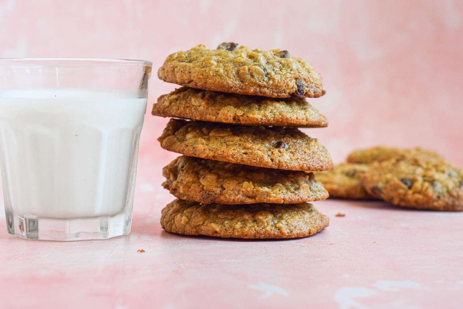 Stack of Oatmeal Banana Cookies Next to a Glass of Milk, and in the Background, More Cookies on the Counter