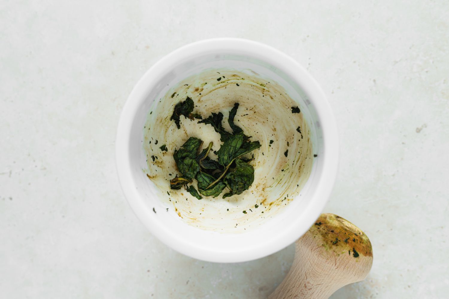 Mashing mint in a bowl for a wax beans recipe.