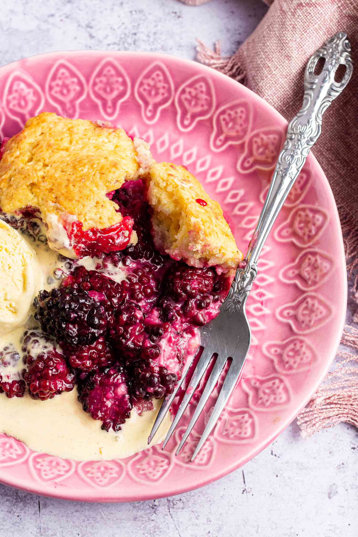 A plate with a piece of easy blackberry cobbler and a scoop of ice cream.