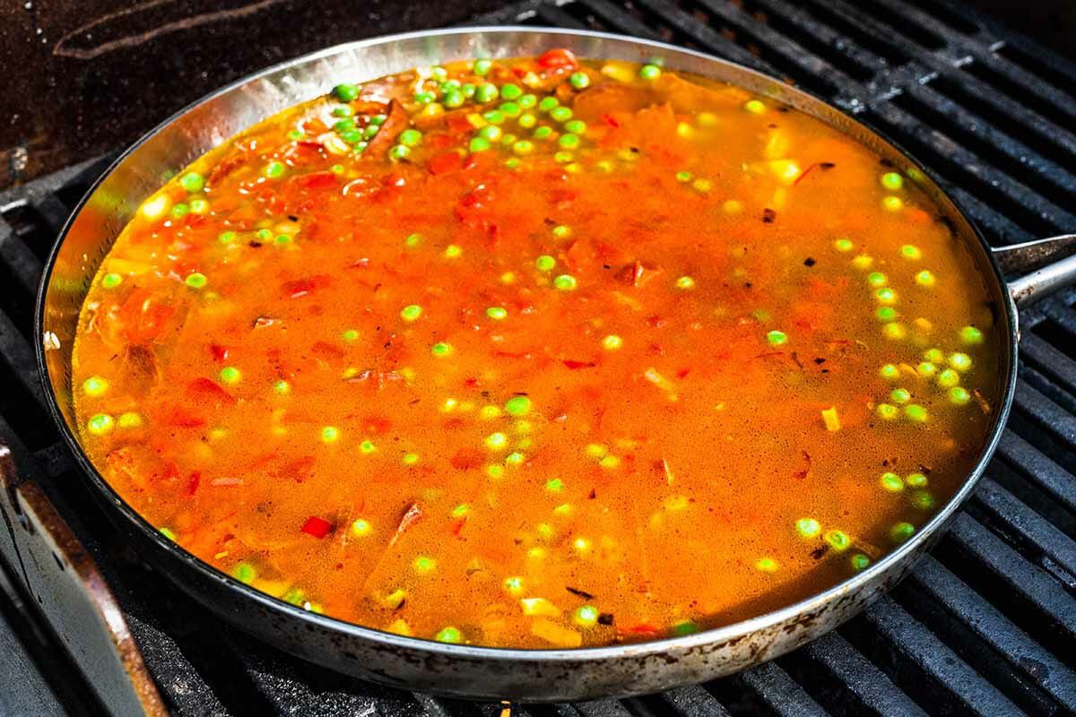 Stock and tomatoes added and to the soffrito base and cooking on a grill