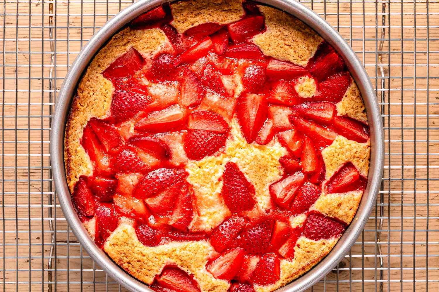 Baked strawberry spoon cake (in a circular pan) cooling on a wire rack