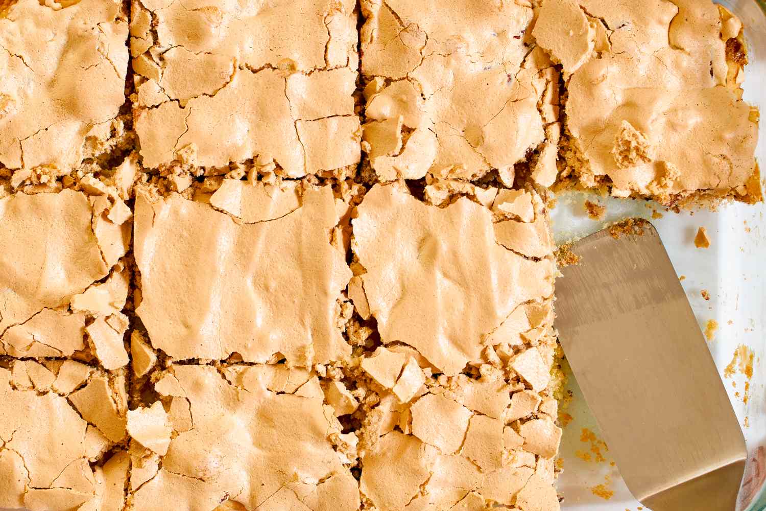 Sliced bar dessert with a cracked top and a serving spatula