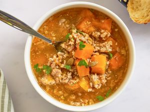 A bowl of butternut squash and sausage soup with a spoon