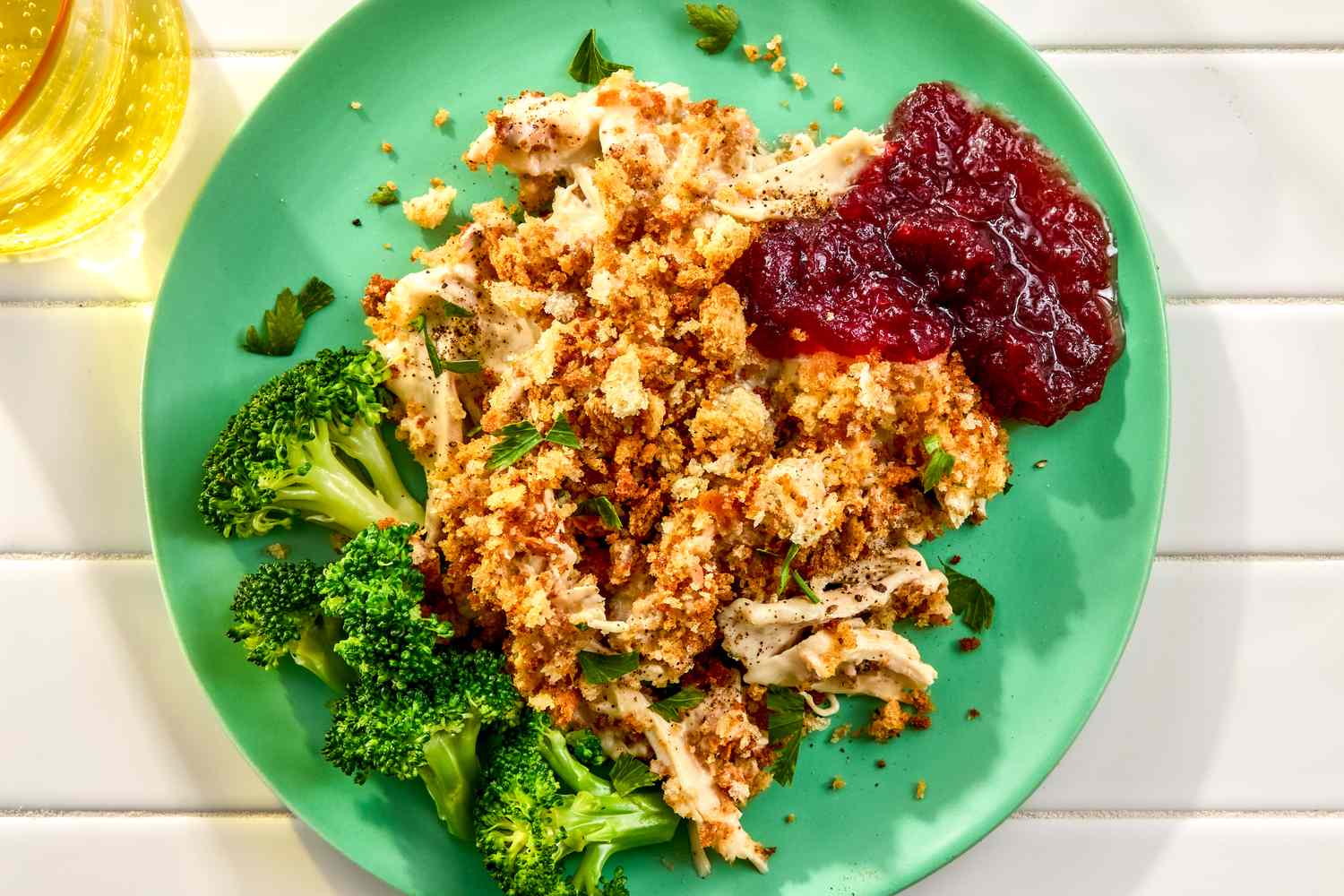 Chicken stuffing casserole served with cranberry sauce and broccoli on a green plate