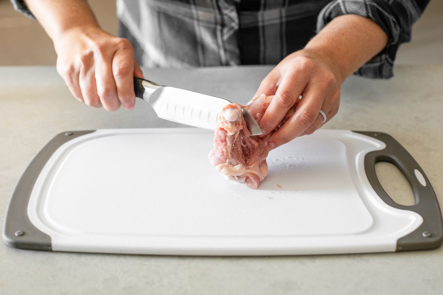 Meat Folded and Held in One Hand, While the Knife Cuts Down the Back of the Bone for How to Debone Chicken Thighs