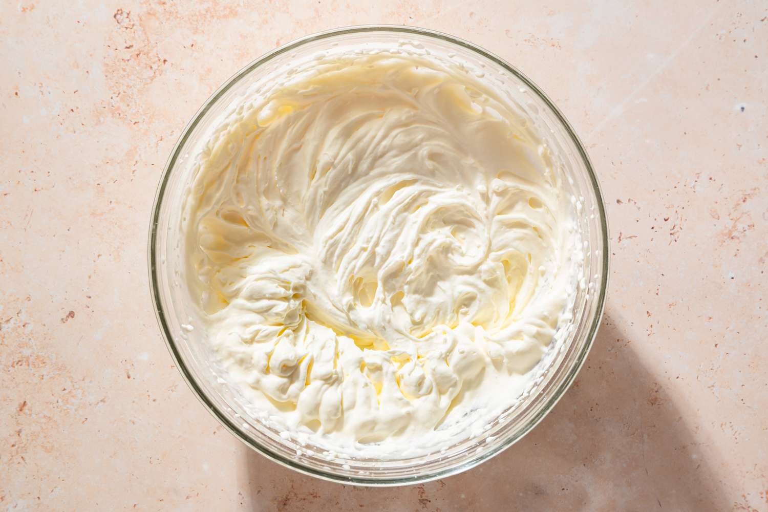 Overhead view of a bowl of heavy cream, powdered sugar, and vanilla whipped for Chocolate Delight recipe