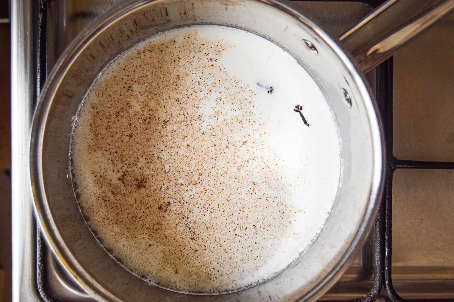 Milk, cloves, and cinnamon heating up in a pot