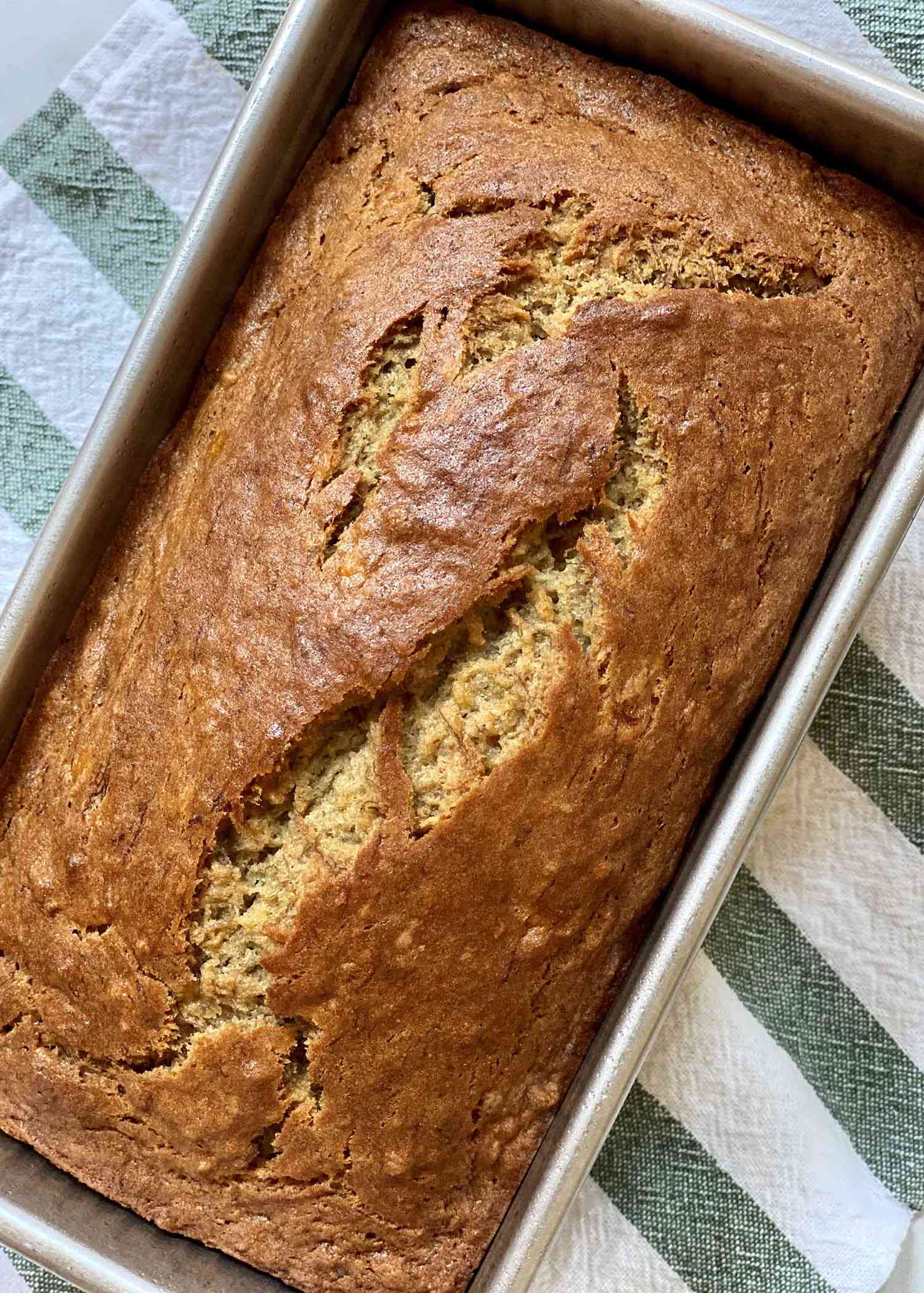 The best gluten free banana bread in a pan with a linen towel underneath.