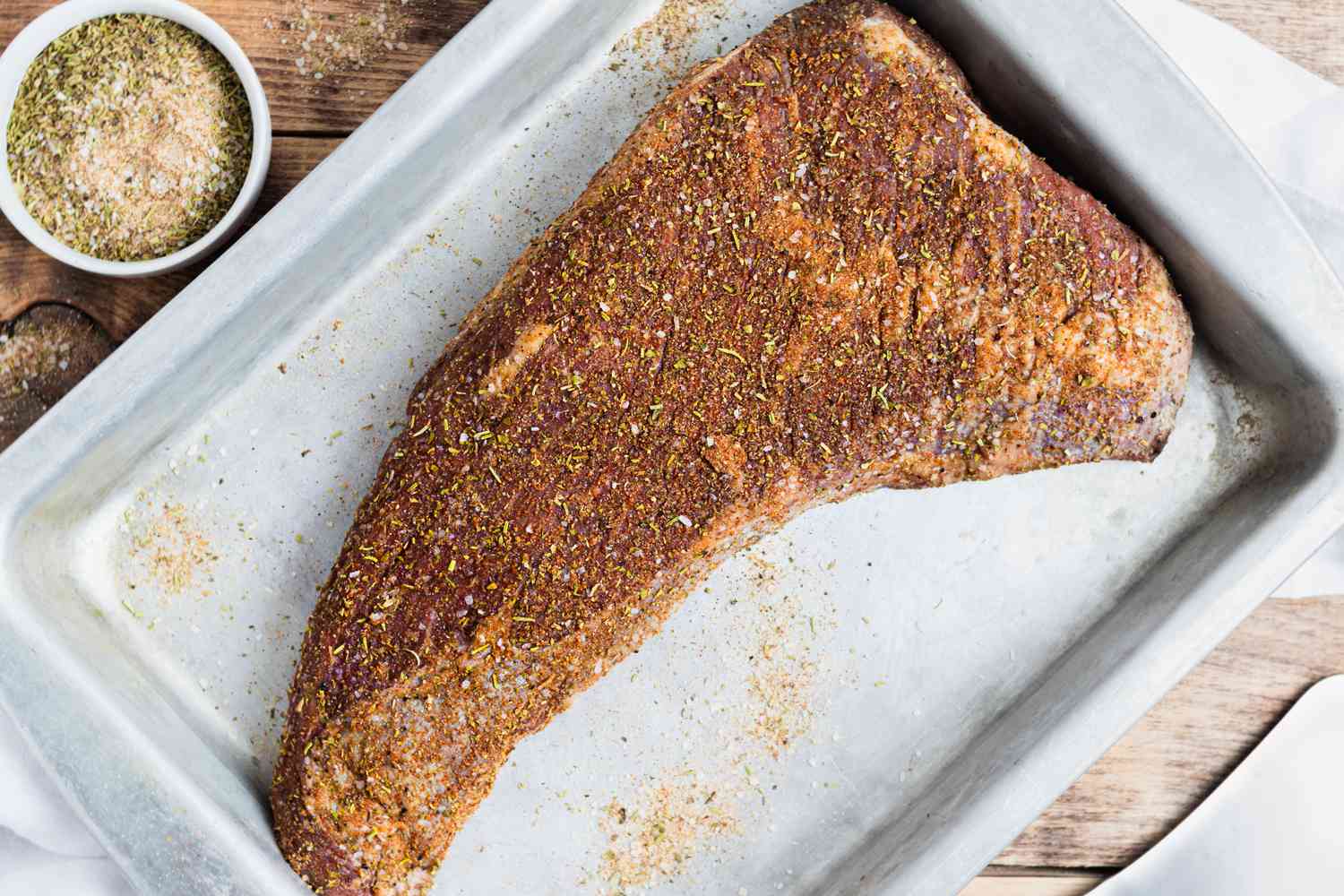 Overhead view of a seasoned steak on a baking sheet for a tri tip recipe.