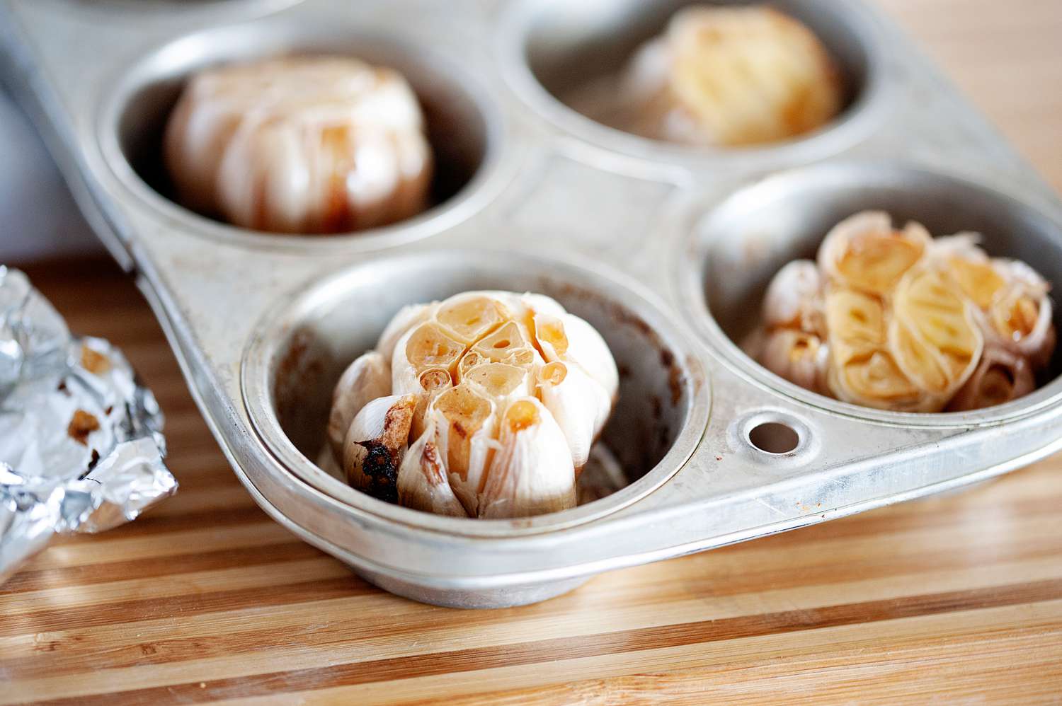 Roasted garlic cloves in a muffin tin.