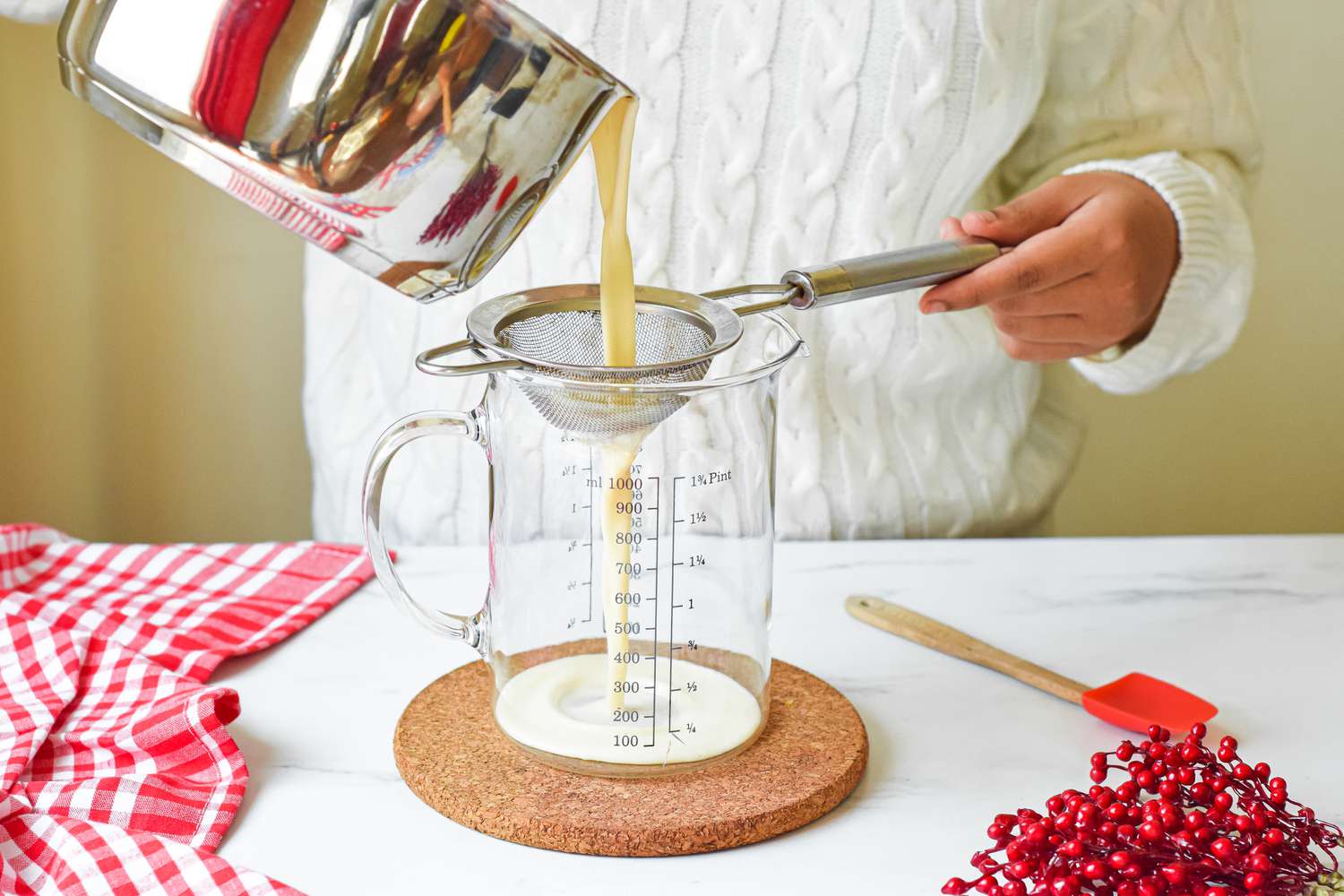 Straining eggnog from a pot into a pitcher