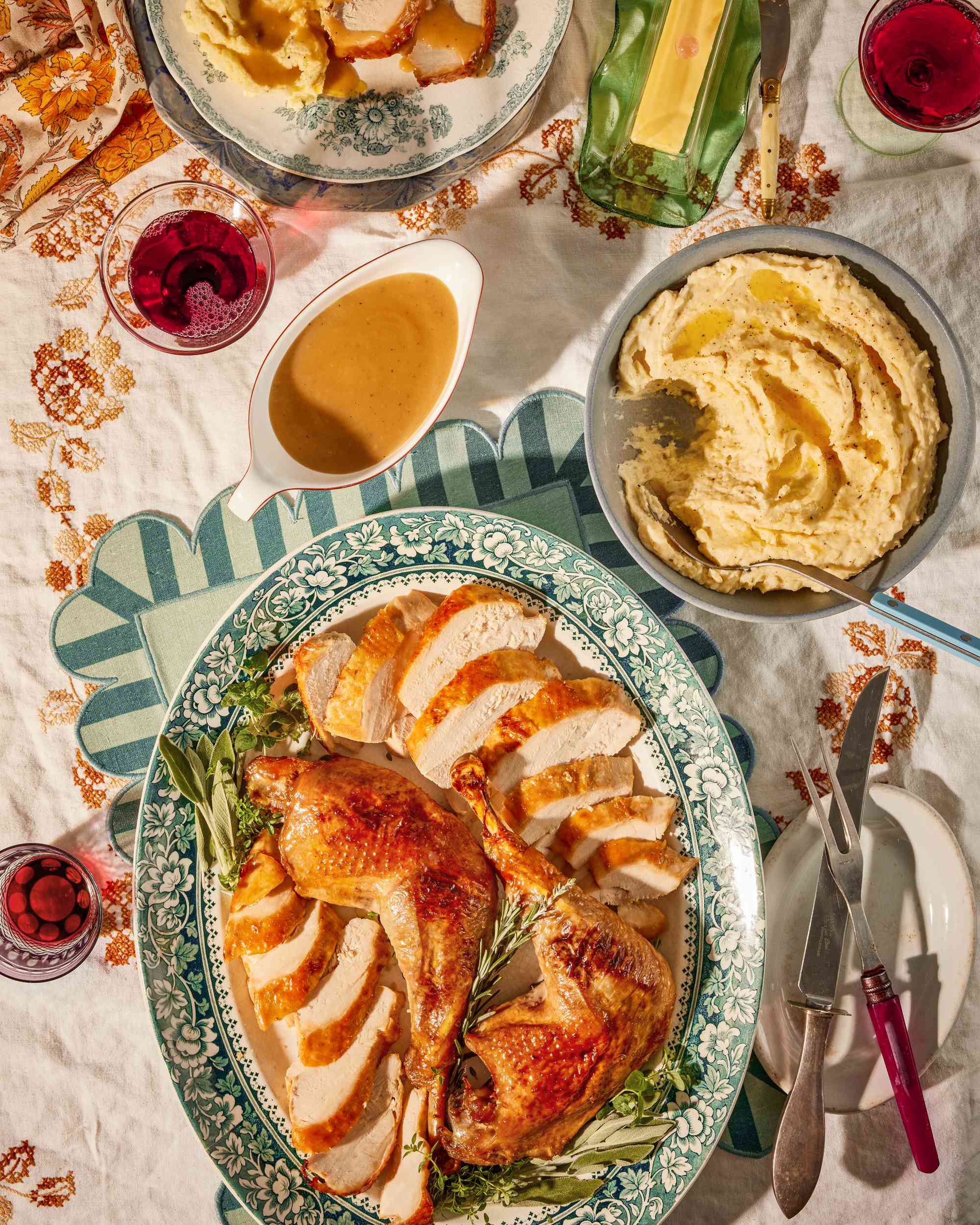 Thanksgiving table with a platter of carved turkey, bowl of mashed potatoes, and gravy boat